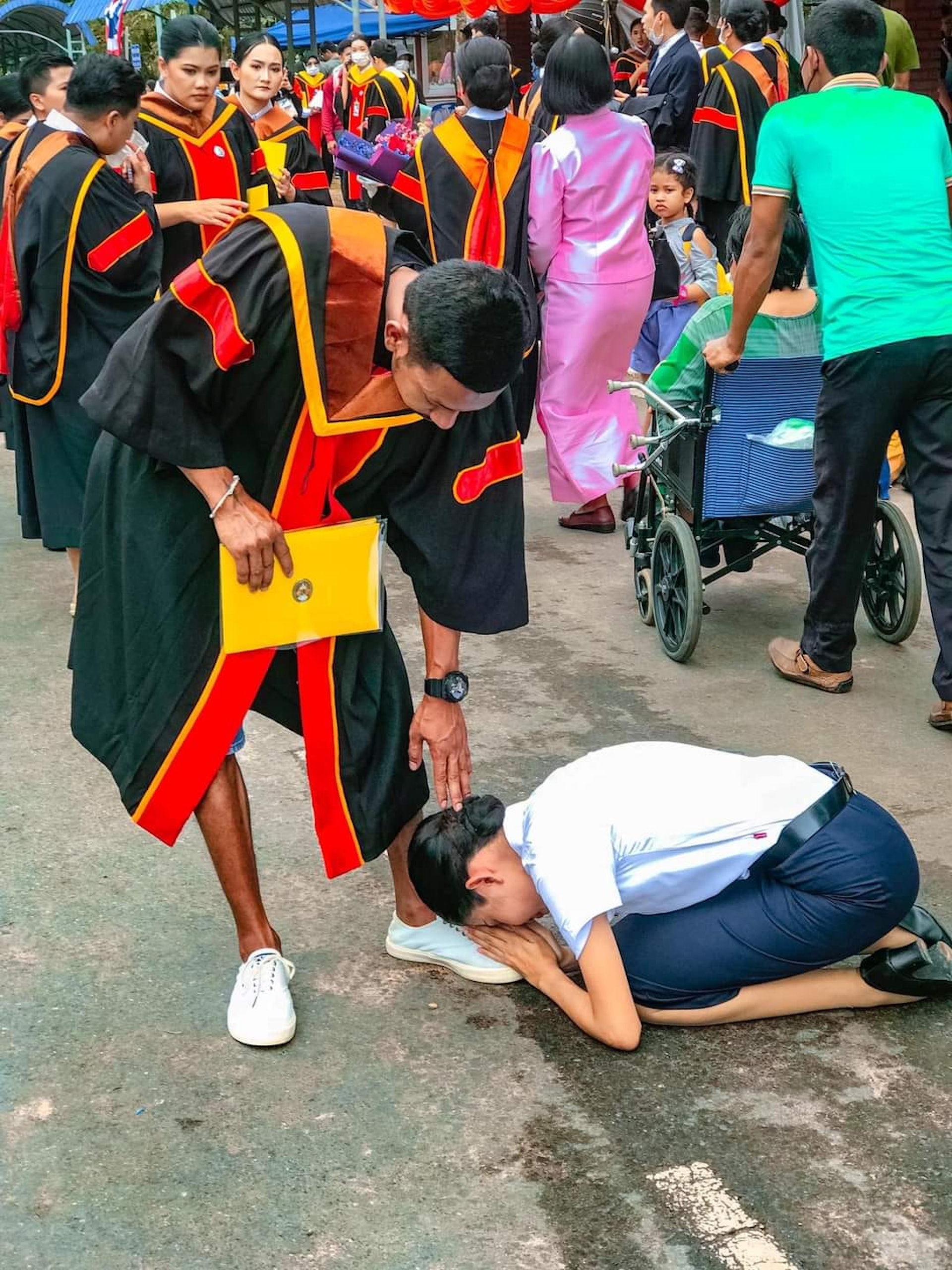 泰國近日瘋傳一組畢業照片，一名女子在畢業典禮上跪地向一名男子行「五體投地」大禮。（網上圖片）