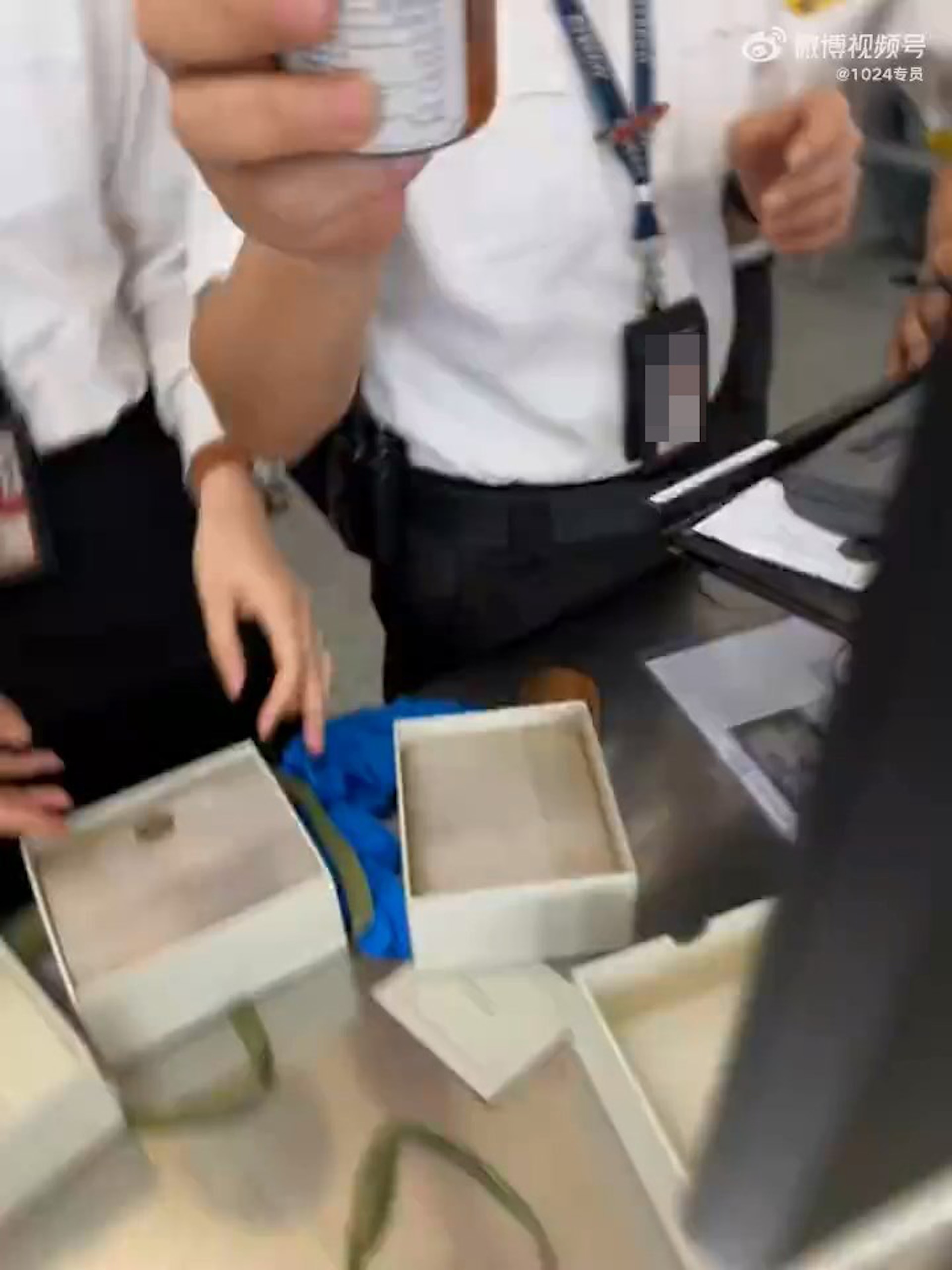 香港機場保安把「XO醬」拆盒取出並解釋原因，內地大媽則在連珠發炮質問保安。（影片截圖）